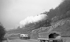 29.3.1968: Die Ehranger 44 1512 aus Richtung Trier - interessanter LKW Verkehr auf der heutigen B51 - im Hintergrund die Brücke zum Heidstocktunnel der Köllertalstrecke (Foto: Reinhard Gumbert)