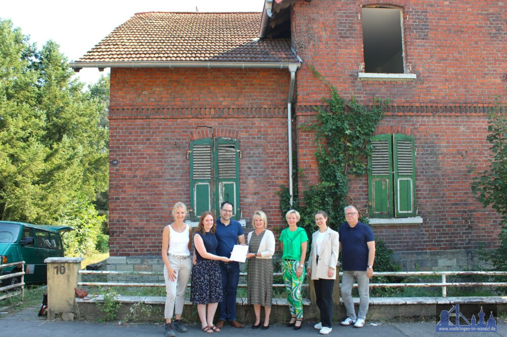 (Stadt VK): V.l.n.r.: Architektin Bärbel Leinenbach, die Eheleute Hakenesch, Oberbürgermeisterin Christiane Blatt, Tanja Schreiner-Zöllner, Paula Zimmermann und Stephan Oellerich (alle Stadt Völklingen) vor dem Sanierungsobjekt in der Althansstraße.