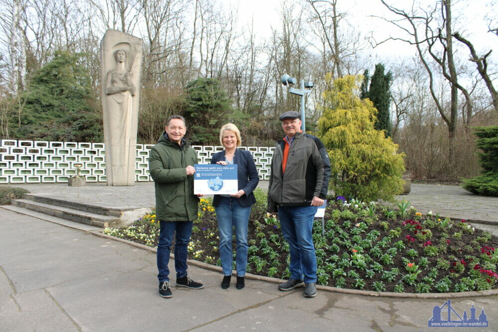 Andreas Sauder, Landesfachstelle Demenz Saarland, Oberbürgermeisterin Christiane Blatt und Fachdienstleiter Tobias Noll vor dem neu bepflanzten Beet am Barbara-Denkmal in Luistenthal (v. l. .n. r.)